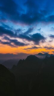 Stunning Mountain Silhouette Sunset Mobile Wallpaper with Vibrant Orange and Blue Sky