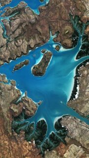 Stunning Satellite View of Turquoise Coastal Waters and Rugged Terrain Wallpaper