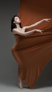Elegant Asian Woman in Flowing Copper Silk Fabric Wallpaper for Mobile