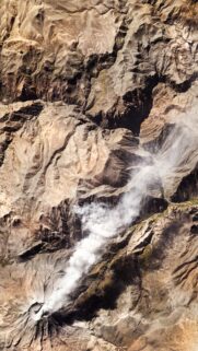 Stunning Aerial View of Volcanic Eruption and Rugged Mountain Terrain Wallpaper
