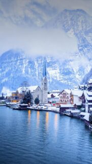 Breathtaking Hallstatt Winter Landscape with Snowy Mountains and Church Mobile Wallpaper