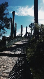 Stone Pathway with Ancient Totems and Tourists Under Blue Sky Wallpaper