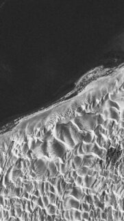 Minimalist Black and White Aerial View of Desert Dunes and Ocean Shoreline Wallpaper