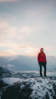 Adventurer Standing on Snowy Mountain Peak Phone Wallpaper