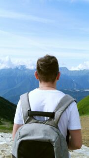 Young Man Standing Before Majestic Mountain Peaks Mobile Wallpaper