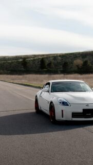 White Nissan 350Z with Red Rims on Desert Road Mobile Wallpaper