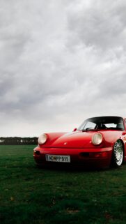 Stunning Red Porsche 911 Sportscar on Grass Meadow Phone Wallpaper