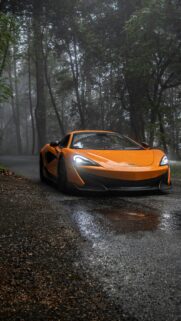 Stunning Orange McLaren Supercar in Foggy Forest Path Mobile Wallpaper