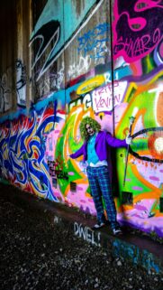 Joker Cosplay Standing in Vibrant Graffiti Alley Mobile Wallpaper