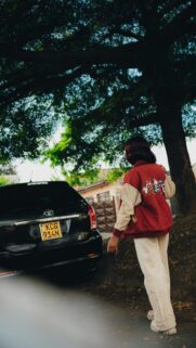 Stylish Woman in Looney Tunes Jacket Walking Near Car Wallpaper