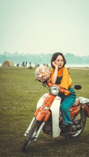 Cute Girl Sitting on Vintage Orange Motorcycle Wallpaper
