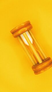 Minimalist Wooden Hourglass on Vibrant Yellow Background Wallpaper