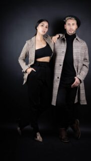Stylish Couple in Plaid Fashion Coats on Black Background Wallpaper