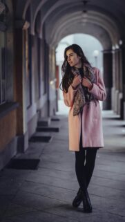 Elegant Woman in Pastel Pink Coat City Archway Mobile Wallpaper