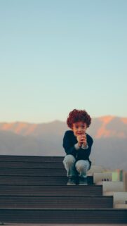 Cute Red-Haired Boy Sitting on Outdoor Stairs Mobile Wallpaper