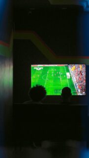 Two Friends Watching Live Football Match on TV Screen Wallpaper