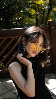 Chic Girl with Yellow Sunglasses and Pearl Earrings Aesthetic Wallpaper