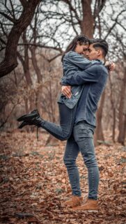 Romantic Couple Embracing in Autumn Forest Phone Wallpaper