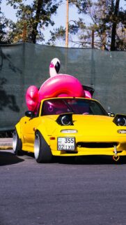 Yellow Mazda Miata NA with Giant Flamingo Pool Float Wallpaper