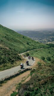 Motorcyclists Riding Through Scenic Green Rolling Hills Wallpaper
