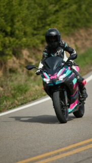Sportbike Rider in Teal and Pink Gear Racing Down the Road Wallpaper