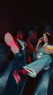 Cool Girl in Cinema with 3D Glasses and Popcorn Mobile Wallpaper