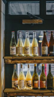 Artisanal Wine Bottles on Rustic Wooden Shelves Mobile Wallpaper