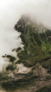 Majestic Mountain Peak Amidst Rolling Mist and Lush Greenery Wallpaper