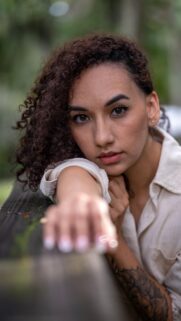 Portrait of a Woman with Curly Hair and Tattoo Mobile Wallpaper