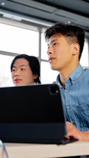 Focused Asian Students Working Together on Tablet Wallpaper
