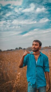 Young Man in Denim Shirt Standing in Golden Field Wallpaper