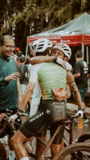 Muddy Cyclists Celebrating Victory After Competitive Mountain Bike Race Wallpaper