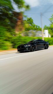 Black Ford Mustang GT Speeding on Sunny Road Mobile Wallpaper