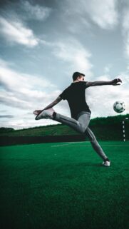 Dynamic Soccer Player Mid-Air Kicking Ball Mobile Wallpaper