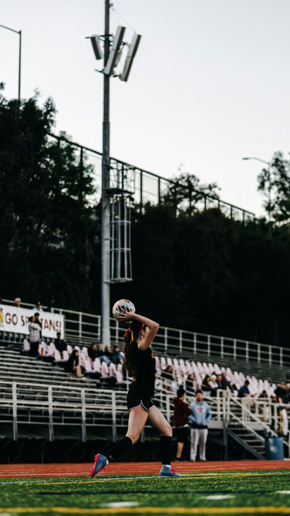 Female Soccer Player Throw-In Action on Sports Field Wallpaper