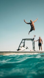 Thrilling Man Jumping into Crystal Blue Ocean Boat Wallpaper