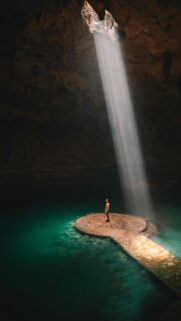 Sunlight Beam in Cenote Cave with Person Mobile Wallpaper