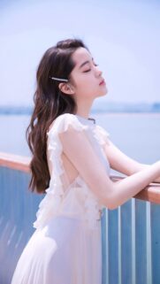 Beautiful Young Woman in White Ruffled Dress Standing by the Sea Wallpaper