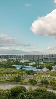 Stunning Aerial View of Urban Cityscape with Lush Green Trees and Blue Sky Wallpaper