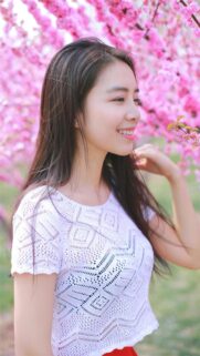 Beautiful Young Woman Smiling Among Blooming Cherry Blossom Trees Wallpaper