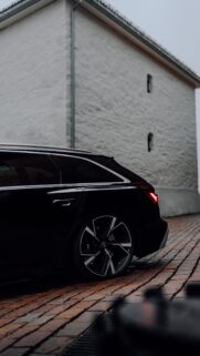 Sleek Black Audi RS6 Avant Parked on Cobblestone Street High Resolution Wallpaper