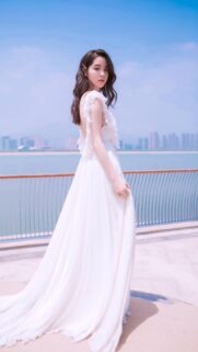 Stunning Young Woman in Elegant White Dress by the Sea Mobile Wallpaper