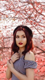 Stunning Portrait of a Woman with Red Hair in a Pink Cherry Blossom Garden Wallpaper