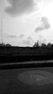 Grayscale Urban Street Art Wallpaper with Manhole and Cloudy Sky