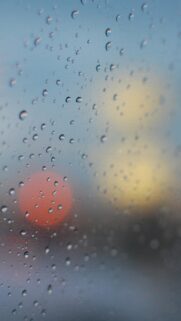 Aesthetic Raindrops on Glass Window with Blurred City Lights Wallpaper