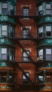 Vintage Brick Building with Emerald Copper Bay Windows and Fire Escape Wallpaper