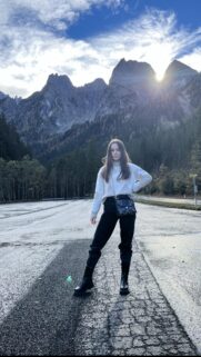 Young Woman Posing Before Majestic Mountain Peaks at Sunset High Quality Wallpaper