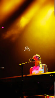 Stunning Female Musician Playing Piano Under Golden Stage Lights Wallpaper