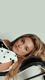 Stunning Blonde Woman in Polka Dot Top Relaxing on Leather Chair Mobile Wallpaper