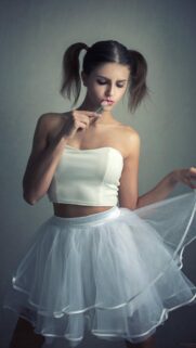 Beautiful Young Woman in White Skirt with Pigtails Eating Lollipop Wallpaper